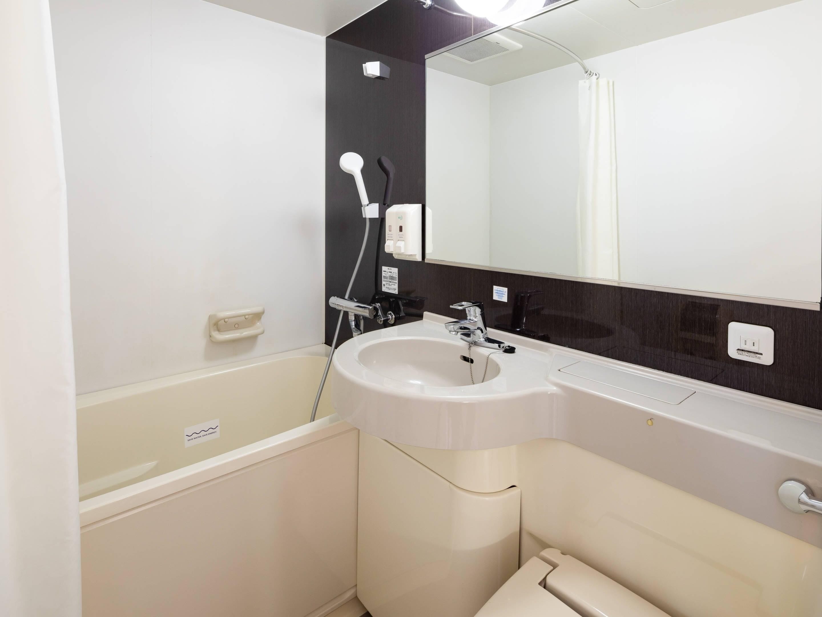 Un baño moderno con lavabo blanco, espejo y ducha.