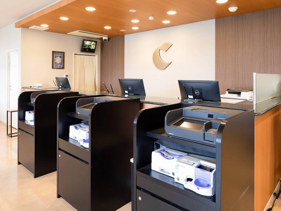 En receptionsområde med tre skranker, hver med en computer og en printer.