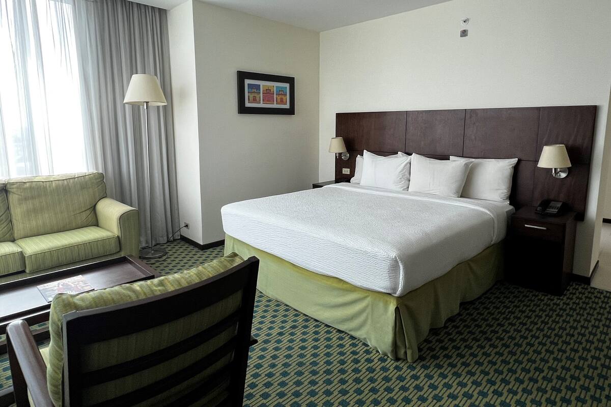 Een hotelkamer met een bed, een bureau, een stoel en een raam met gordijnen.