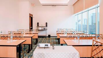 A conference room with tables, chairs, a projector, and a microphone.