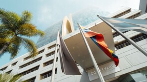 Un edificio moderno con fachada de vidrio, palmeras y banderas.