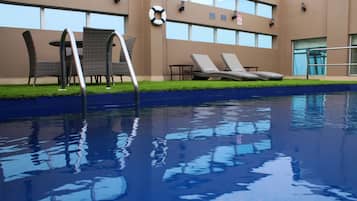 Relax by the pool surrounded by lush greenery and comfortable lounge seating.