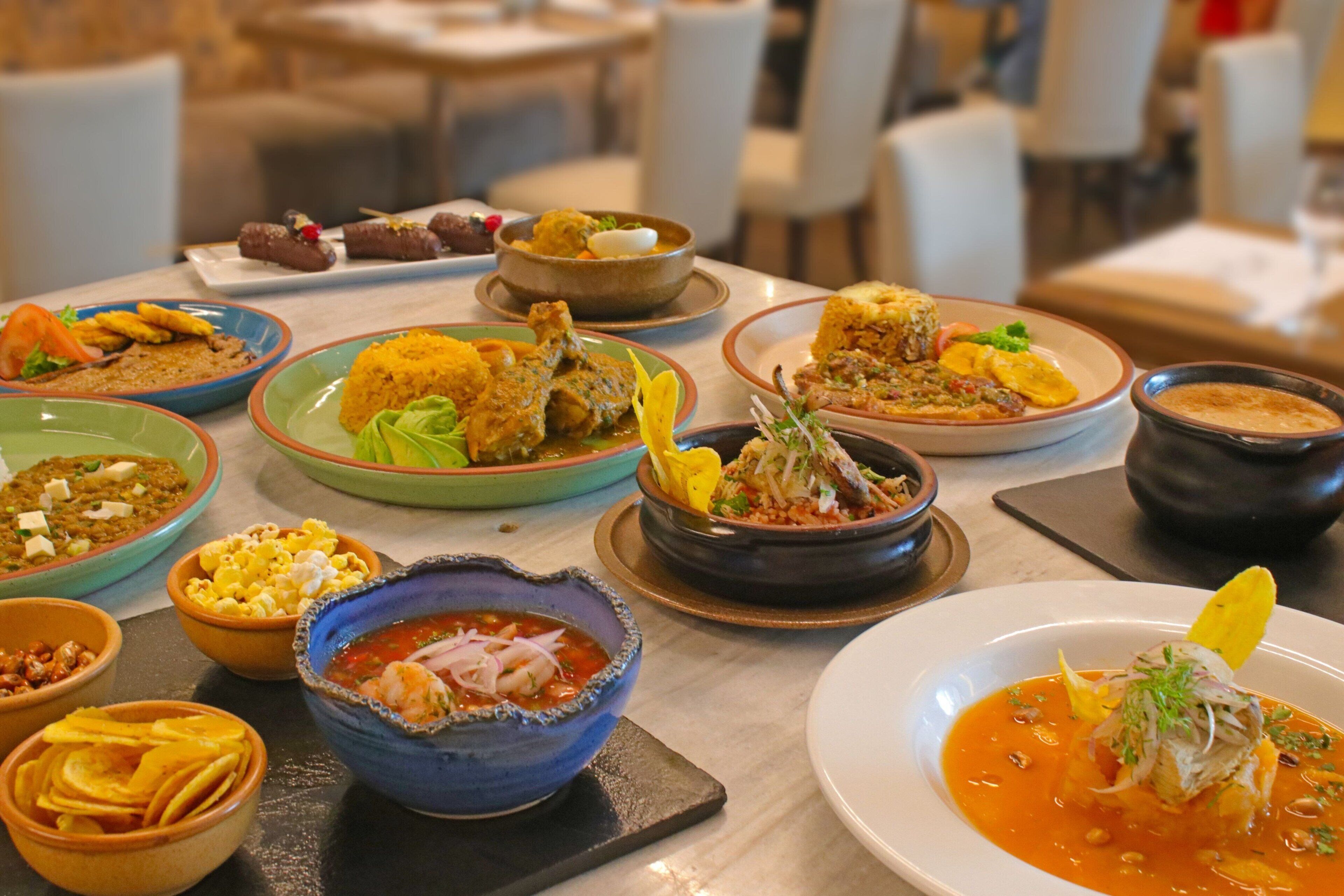 Diversos pratos sobre uma mesa, incluindo sopas, arroz e carnes, indicando um ambiente de restaurante.