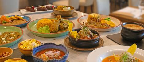 Diversos pratos sobre uma mesa, incluindo sopas, arroz e carnes, indicando um ambiente de restaurante.