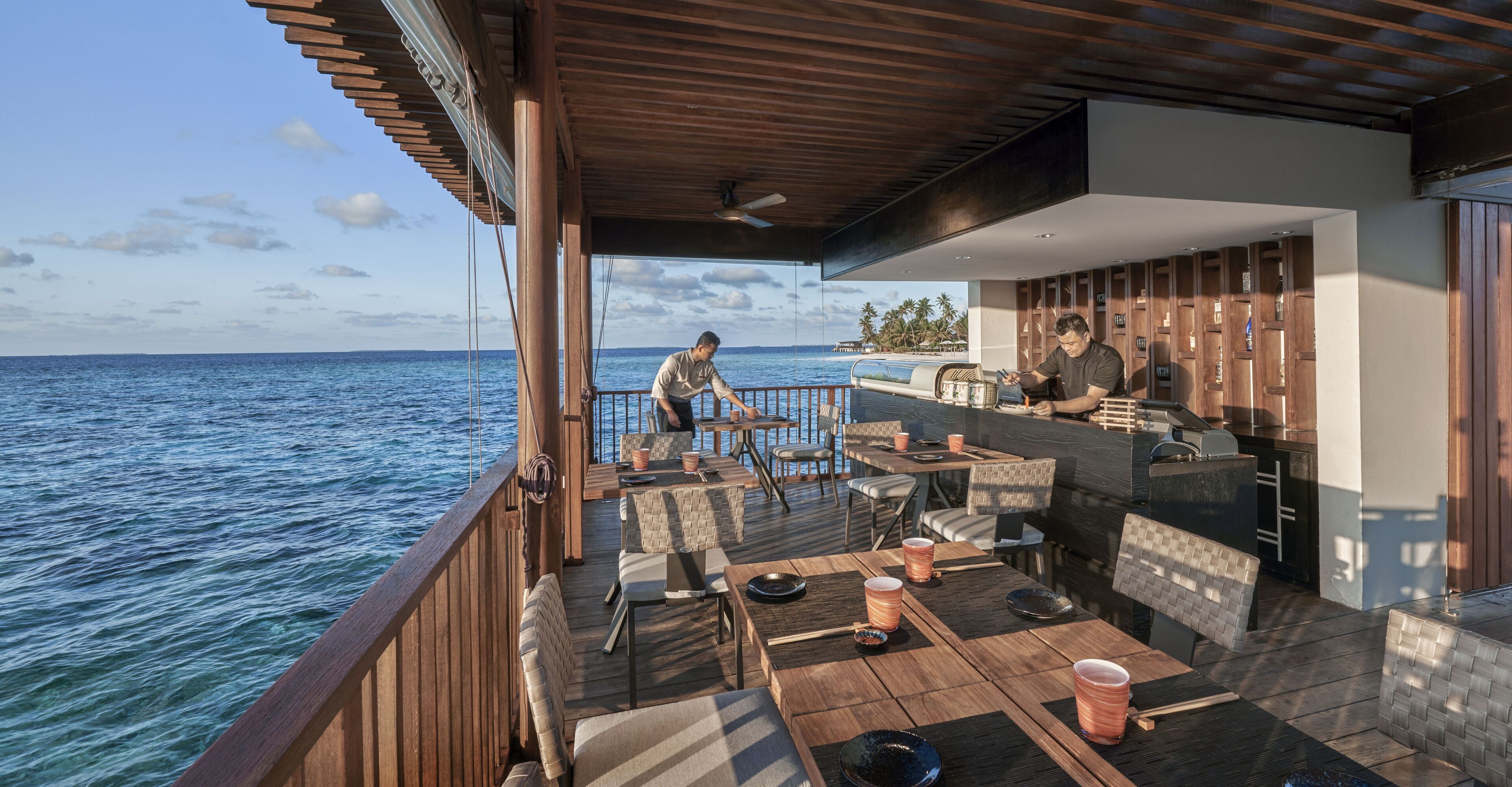 En terrass med utomhusmöbler, en bar och utsikt över havet.