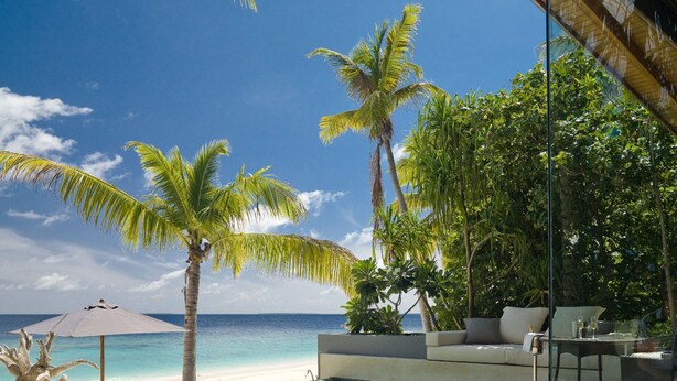 A poolside area with a view of the ocean, palm trees, and a seating area with a table and chairs. - Park Hyatt Maldives Hadahaa (Hadahaa)