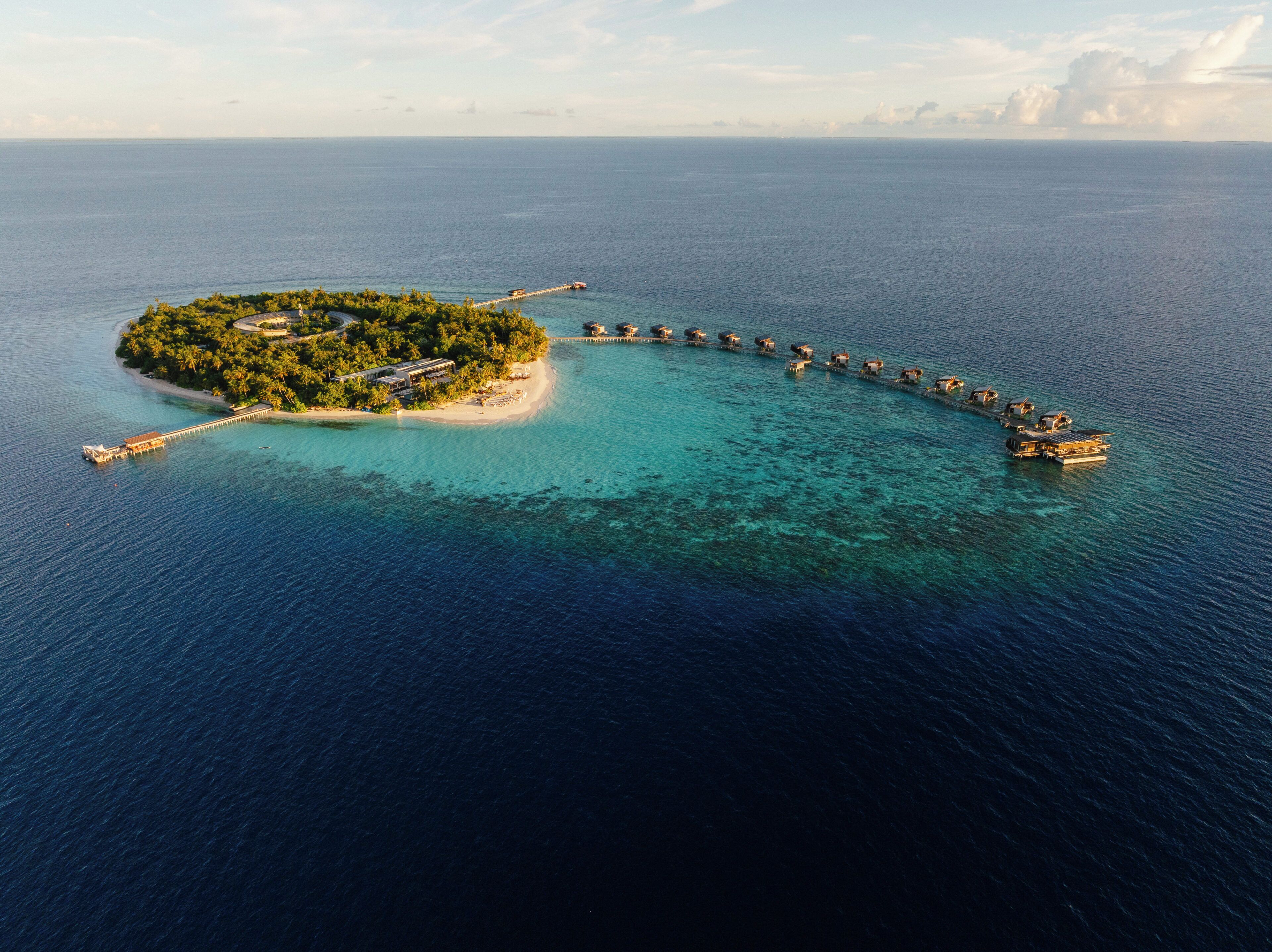 Une île dotée d’une jetée menant à des bungalows sur pilotis.