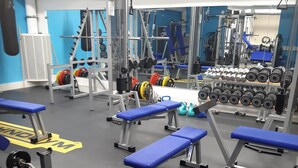 A gym with blue benches, weightlifting equipment, and various exercise machines. - Hotel K5 Levi (Kittila)
