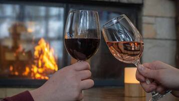 Dos personas sosteniendo copas de vino con una chimenea de fondo.