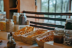 Un bufé de desayuno con diversos productos de panadería y acompañamientos.
