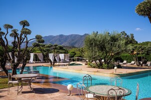 Una piscina al aire libre, sombrillas, sillones reclinables de piscina