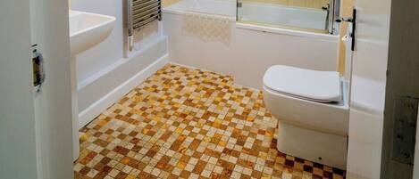 Ein Badezimmer mit Schachbrettboden, einer Badewanne, einer Toilette und einer gläsernen Duschkabine.