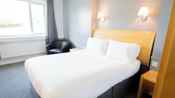 Una habitación de hotel con una cama grande, una silla, una mesita de noche y un ventanal con cortinas.