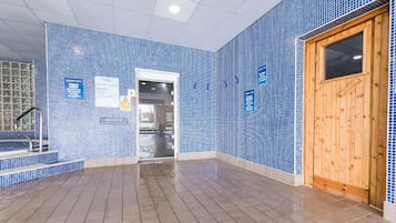 A tiled indoor pool area with a wooden door and a visible exit.