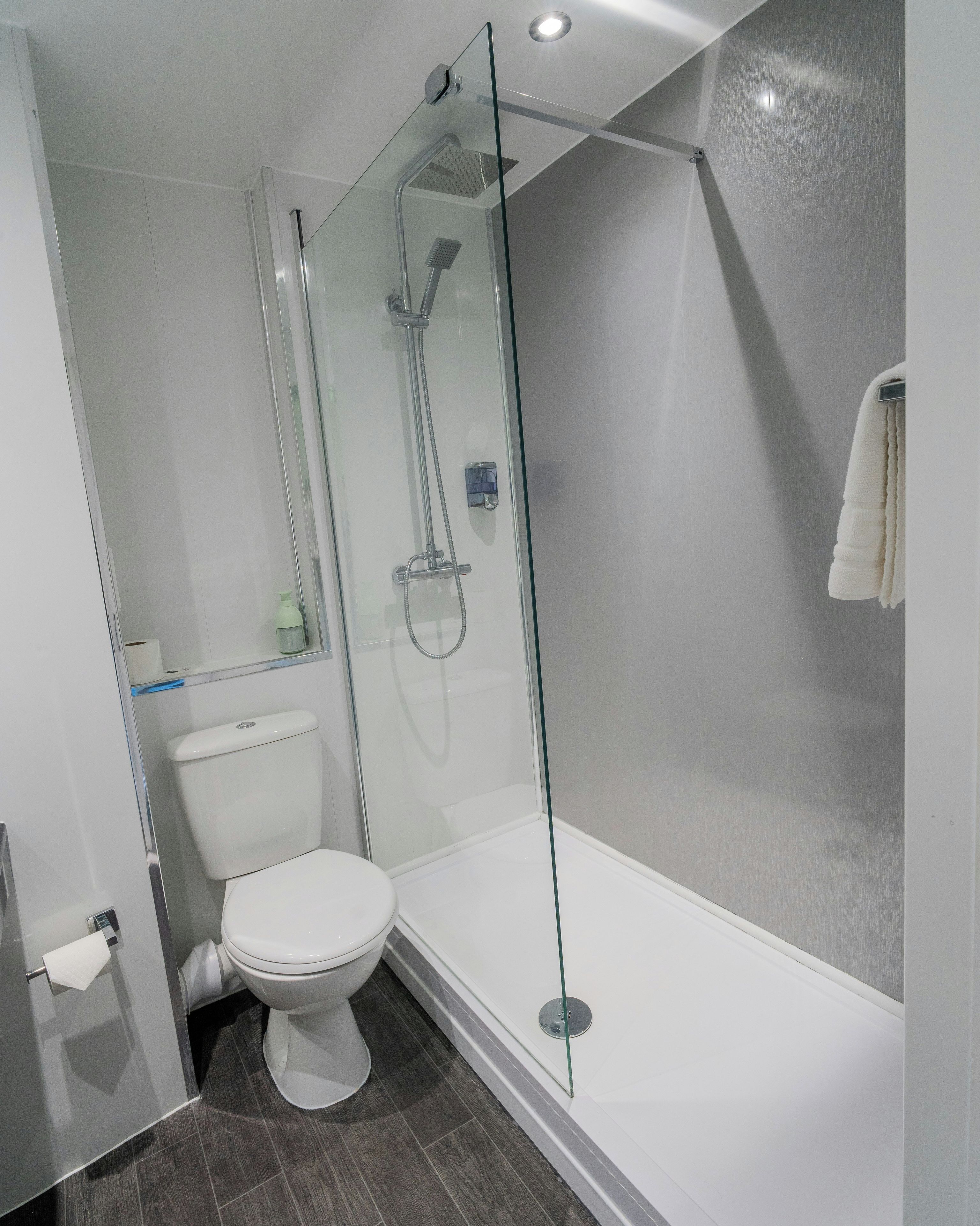 Un baño moderno con ducha acristalada, inodoro blanco y bañera.