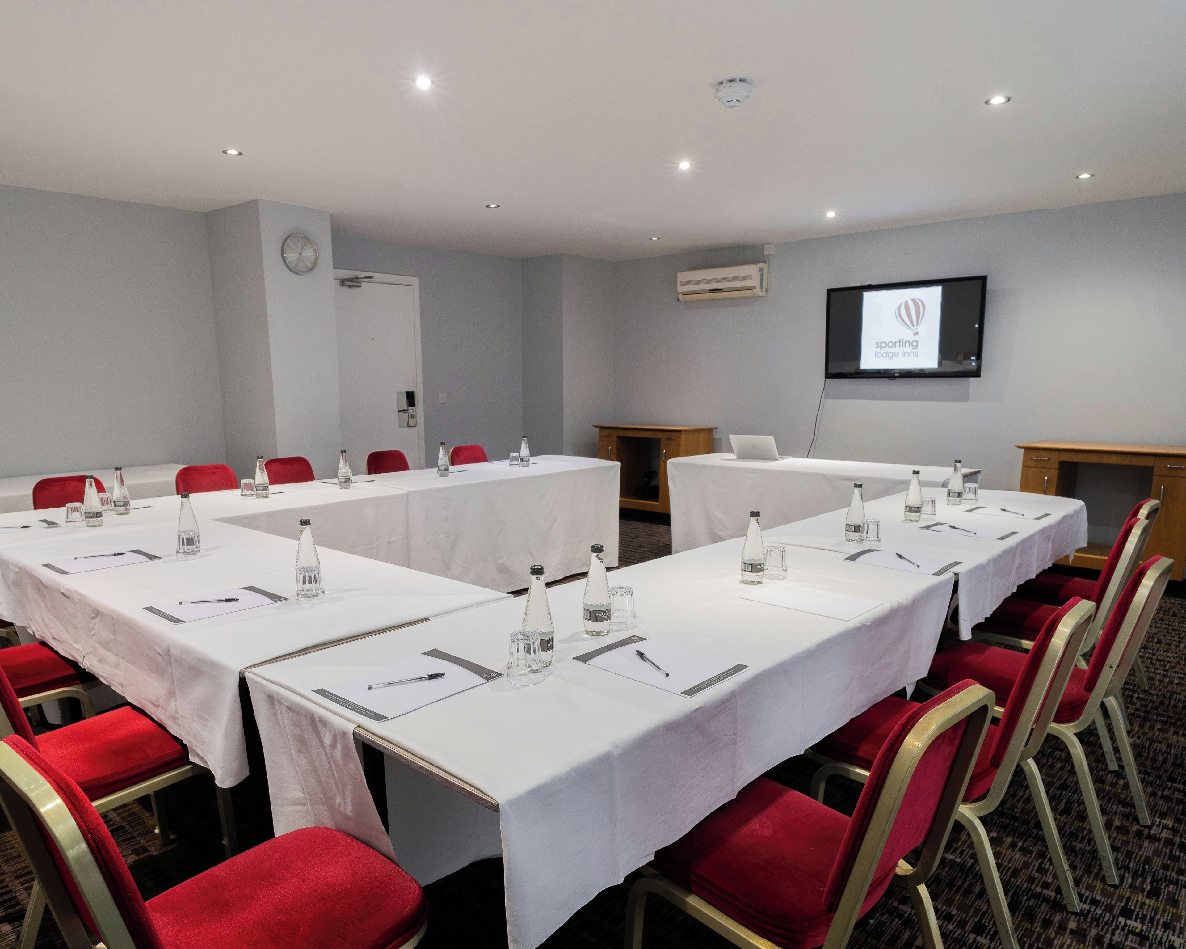 A conference room with tables set for meetings, equipped with water bottles, pens, and notepads.