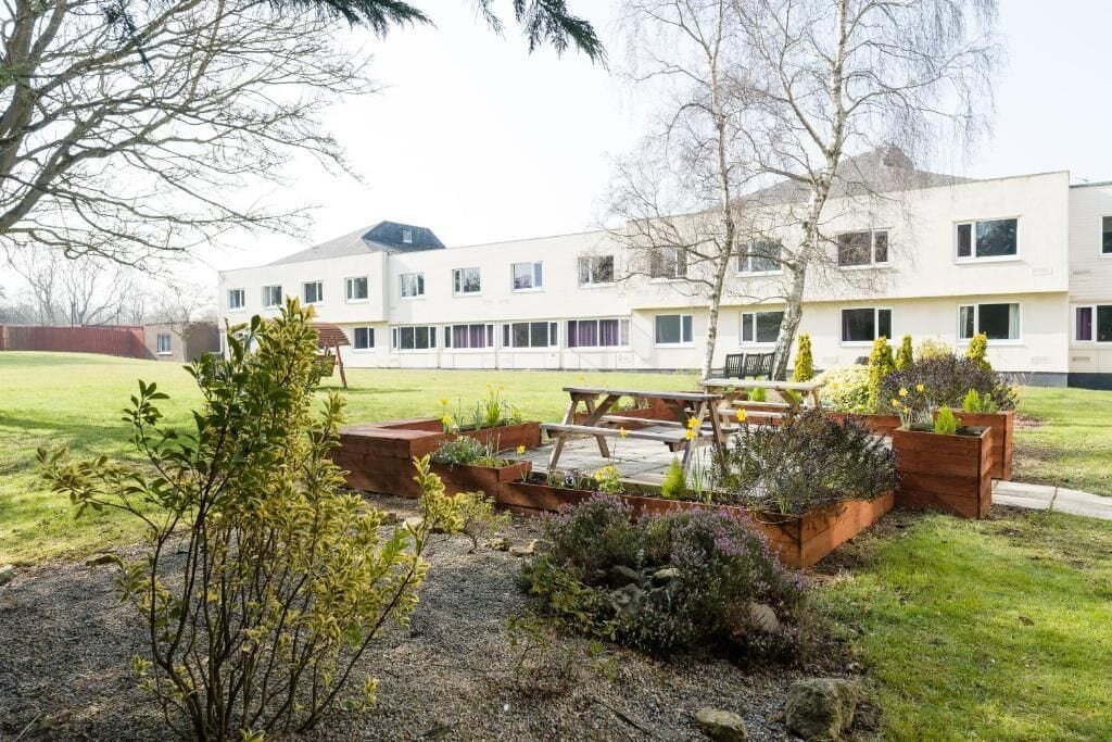 A residential building with a courtyard, outdoor seating, and a well-maintained garden.