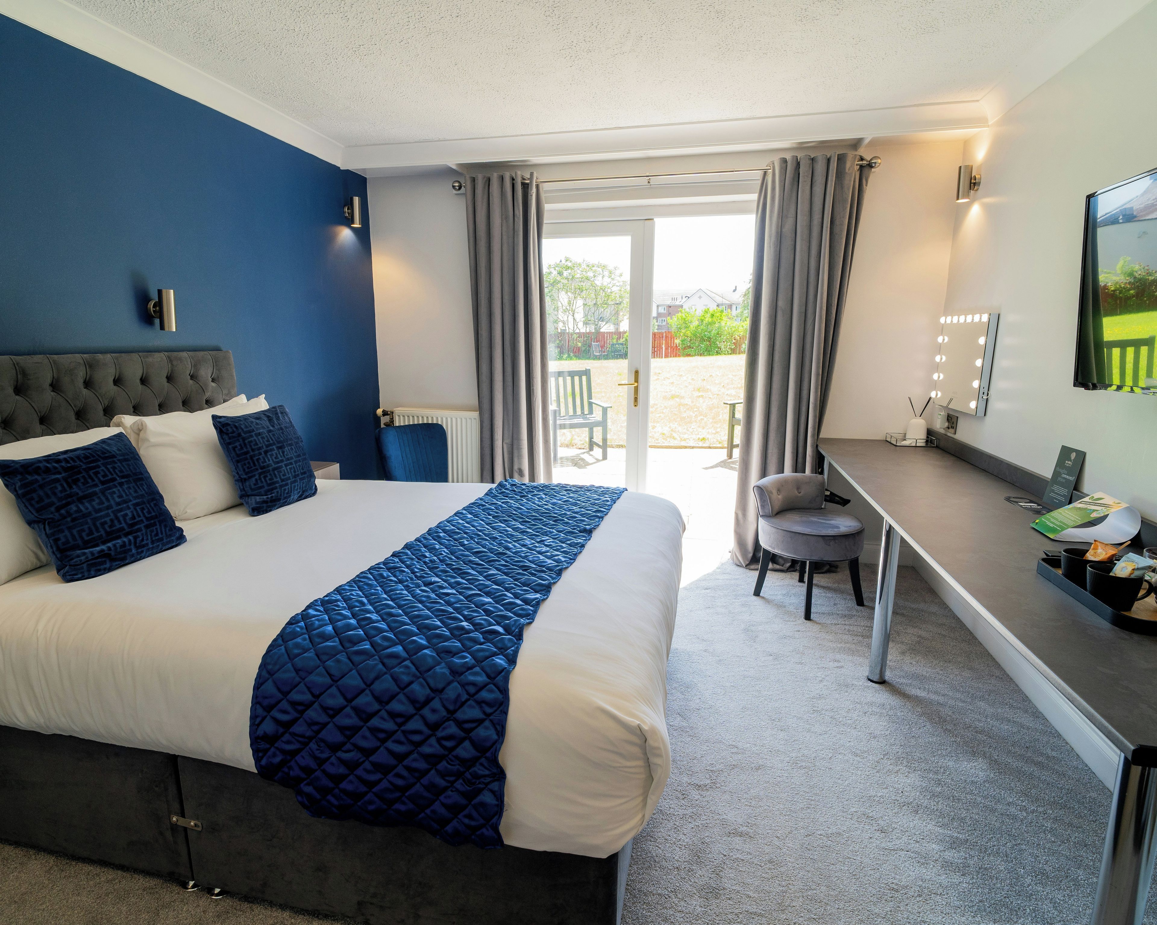 A hotel room with a bed, a desk, and a chair.