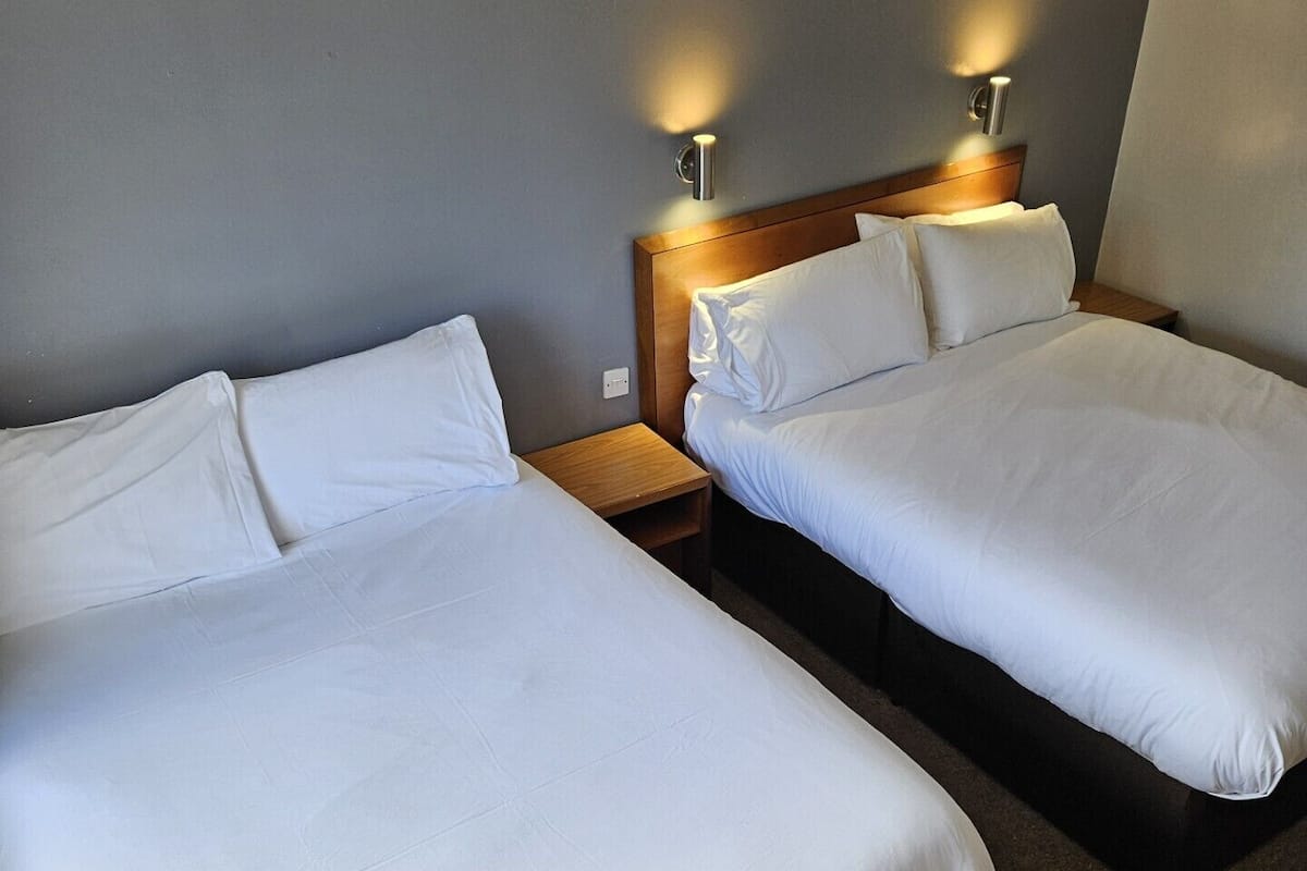 Two single beds with wooden headboards, a nightstand between them, and a wall-mounted light fixture.