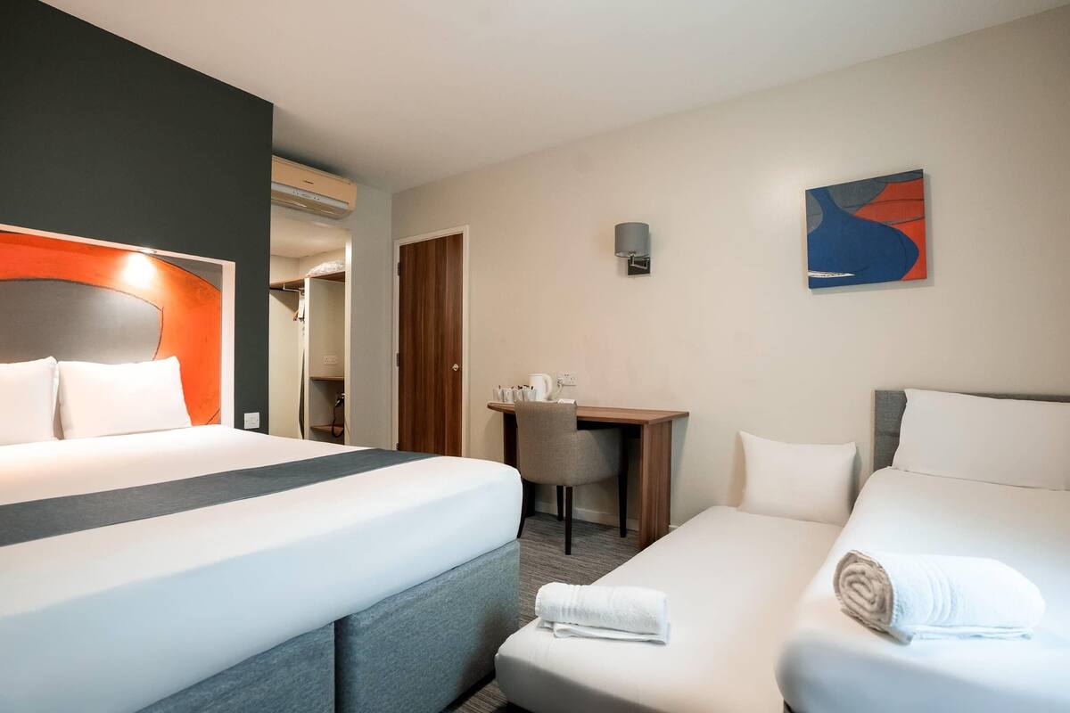 A hotel room with two beds, a desk, and a chair.