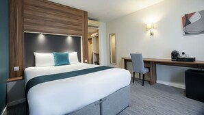 A hotel room with a large bed, a desk, and a chair. - Ramada by Wyndham London Stansted Airport (Bishop's Stortford)