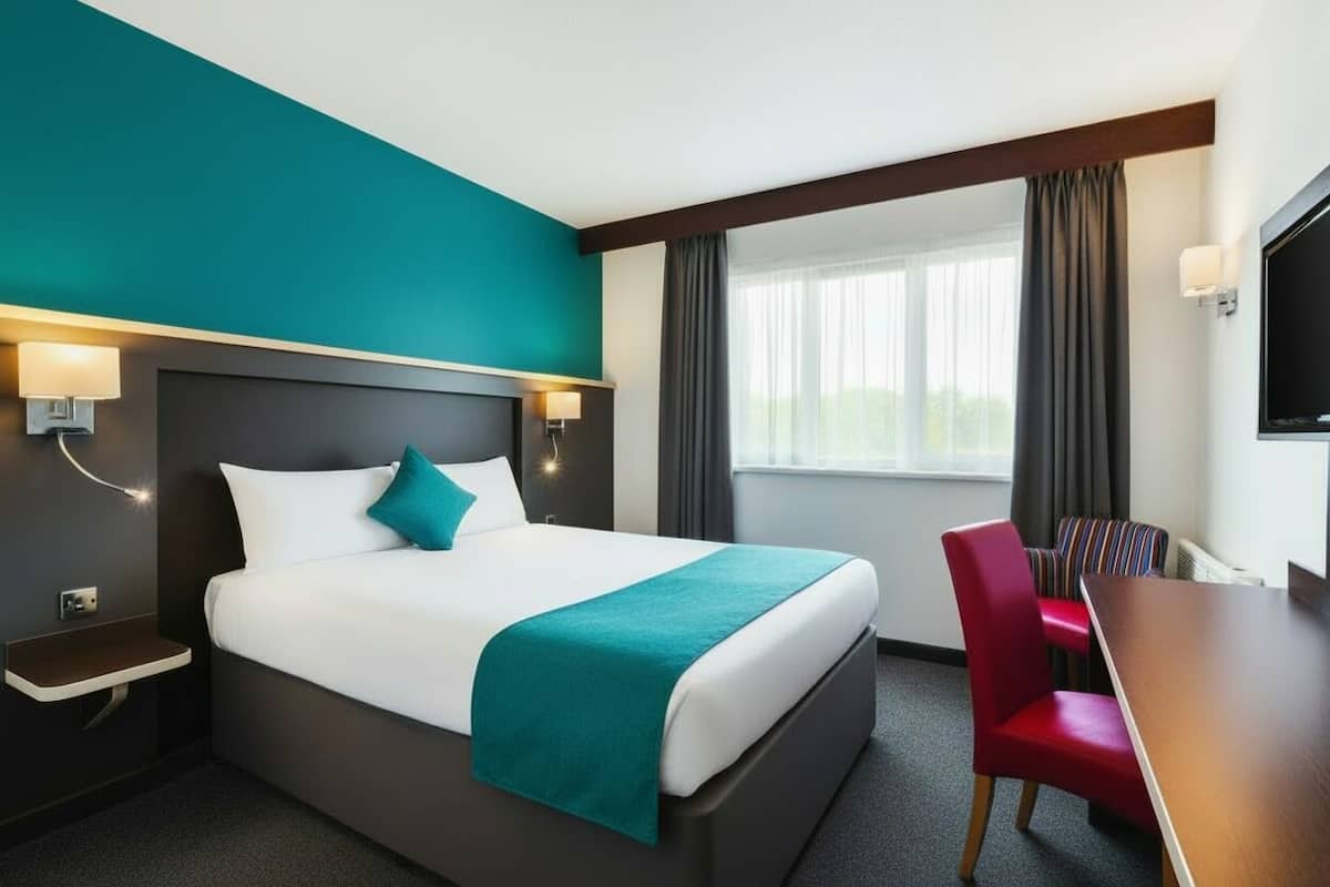 Ein Hotelzimmer mit einem großen Bett, einem Schreibtisch und einem Stuhl.