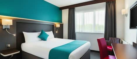 A hotel room with a large bed, a desk, and a chair.