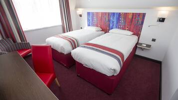 Habitación de hotel con dos camas, una silla roja, una mesa de madera y un cuadro abstracto colorido en la pared.