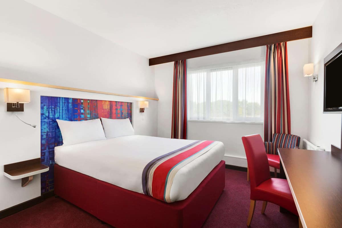 Ein Hotelzimmer mit einem großen Bett, einem Schreibtisch und einem Stuhl.