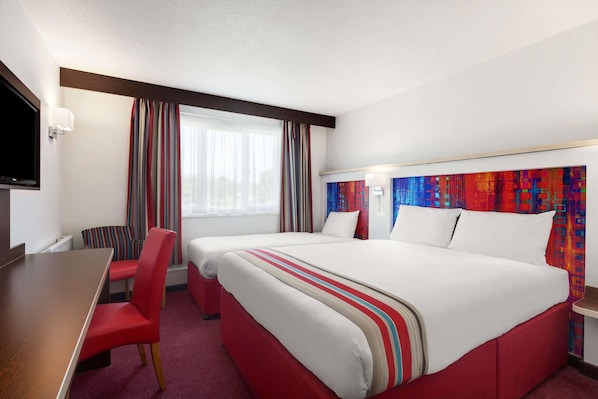 Habitación de hotel con dos camas, un escritorio y un televisor.