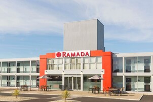 Um edifício moderno com fachada destacada em vermelho e branco, exibindo o nome 'RAMADA' e várias janelas de vidro.
