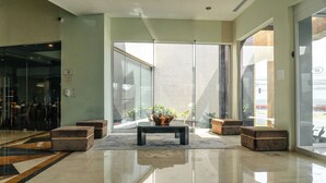 Eine moderne Lobby mit Glastür, einem zentralen Couchtisch und Sitzbereichen.