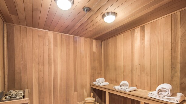 Eine Holzsauna mit Bänken und Ablagen für Handtücher.
