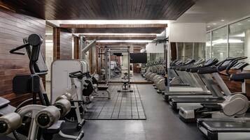 A gym with treadmills, weight machines, and a mirrored wall.