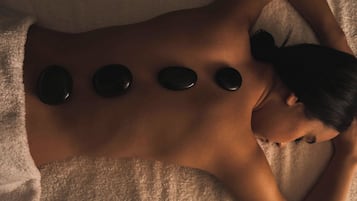 Una persona recibiendo un masaje en la espalda con piedras calientes.