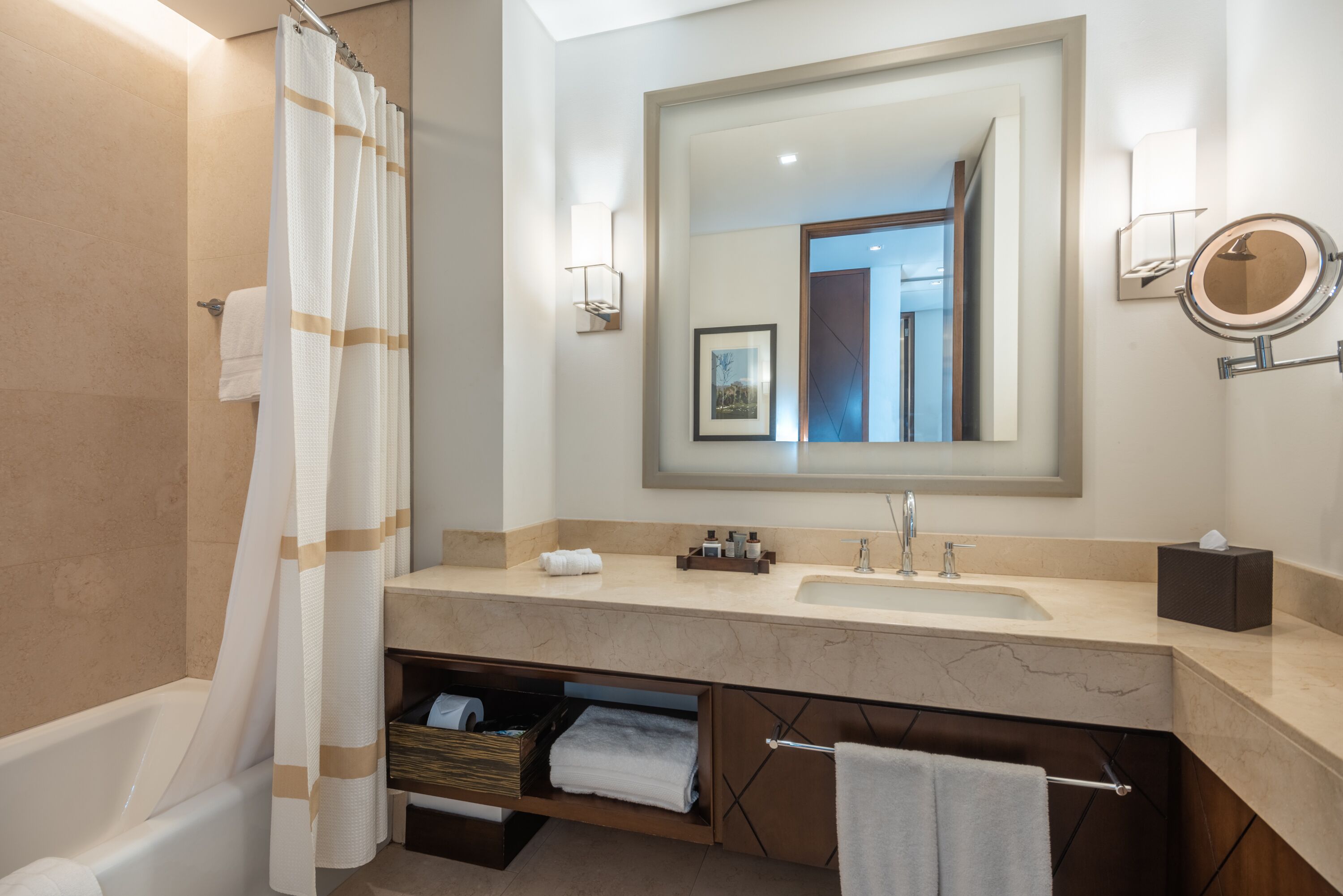 Une salle de bain moderne avec une baignoire, un grand miroir, un lavabo et un meuble-lavabo avec espace de rangement.