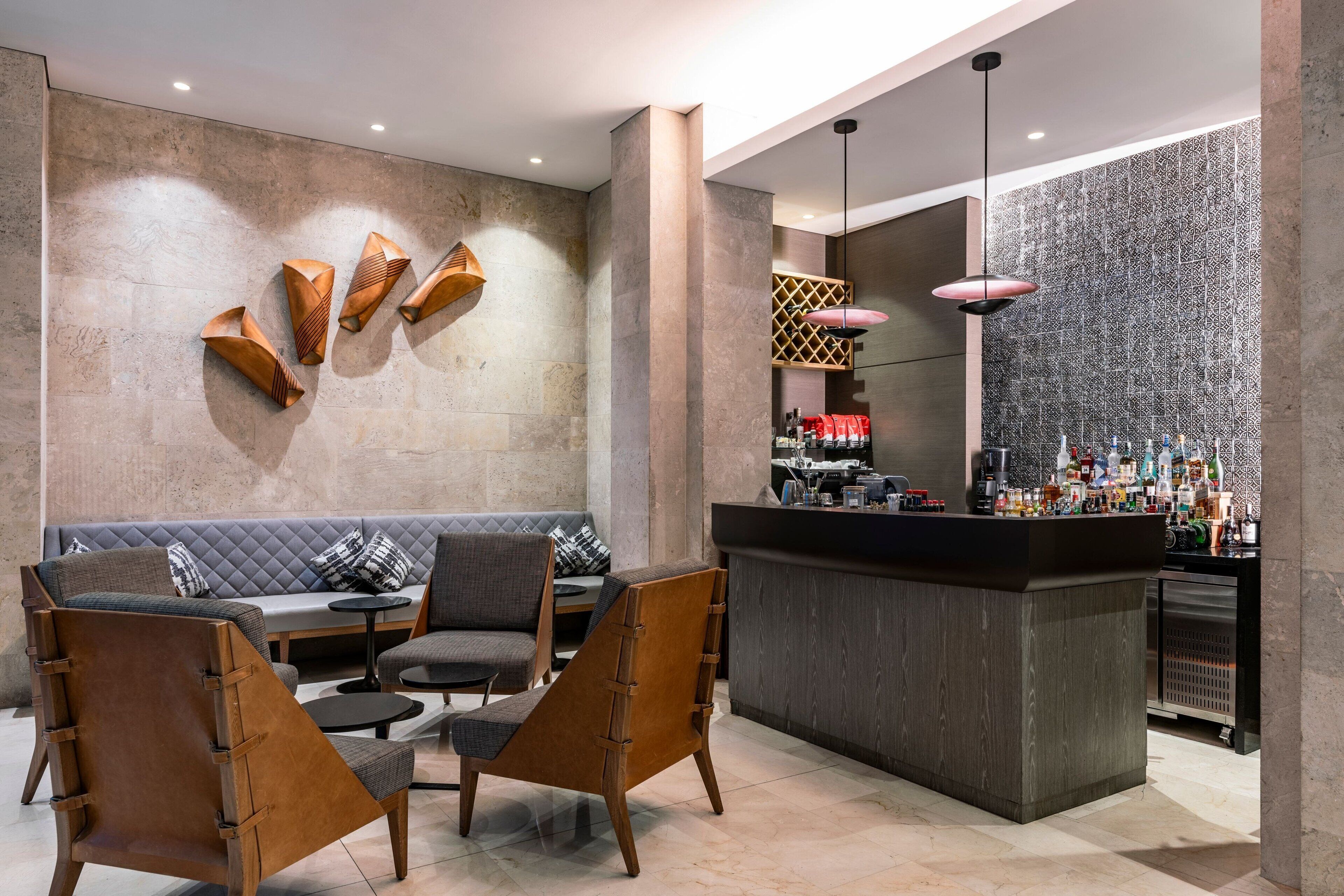 A modern bar area with a seating arrangement, a bar counter, and a patterned wall.