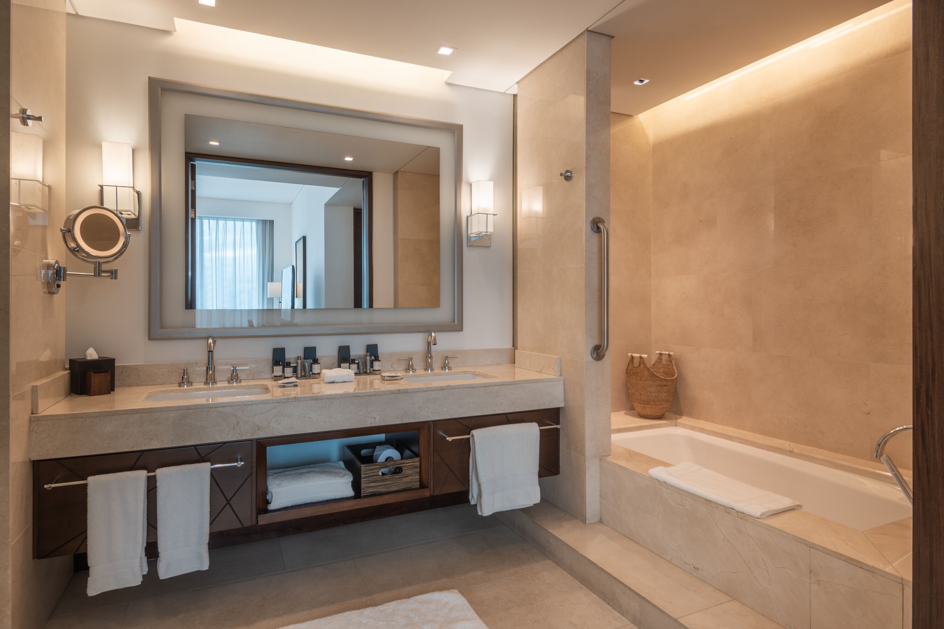 Un baño moderno con un espejo grande, lavamanos dobles, una bañera y un perchero para toallas.