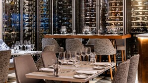 Un restaurante con varias mesas dispuestas para comer, rodeado por una bodega con numerosas botellas.