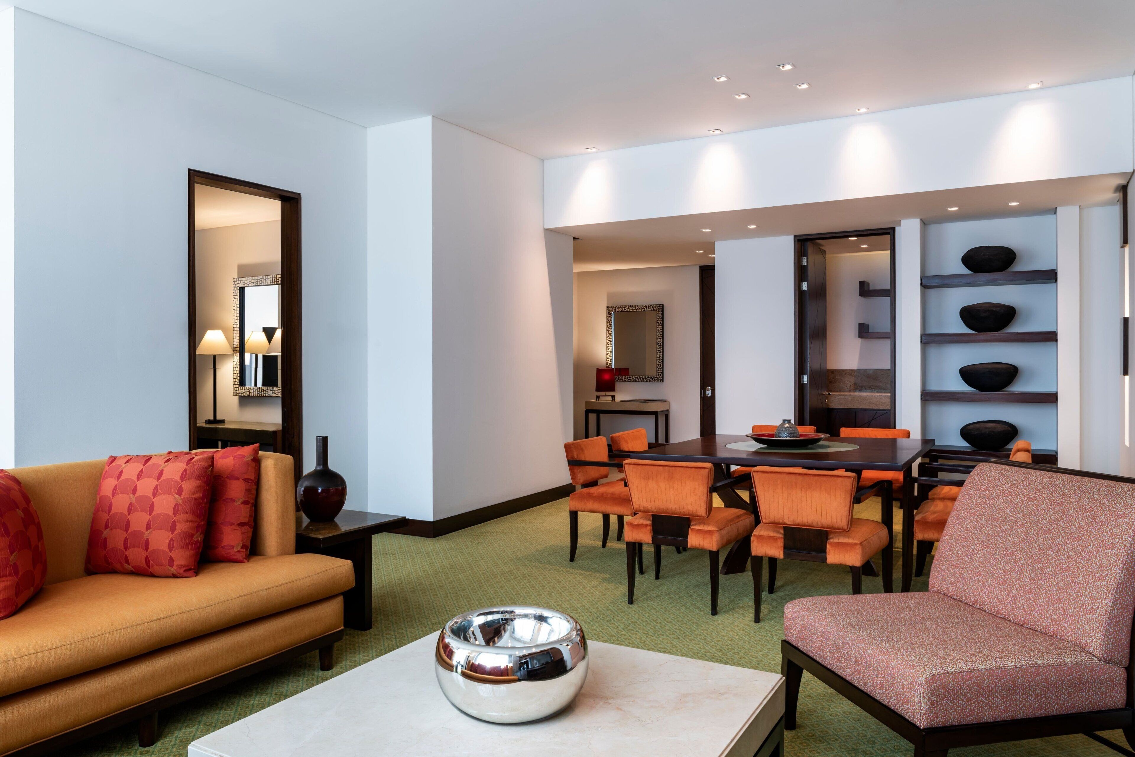 A modern living room with a sofa, armchair, and dining area.