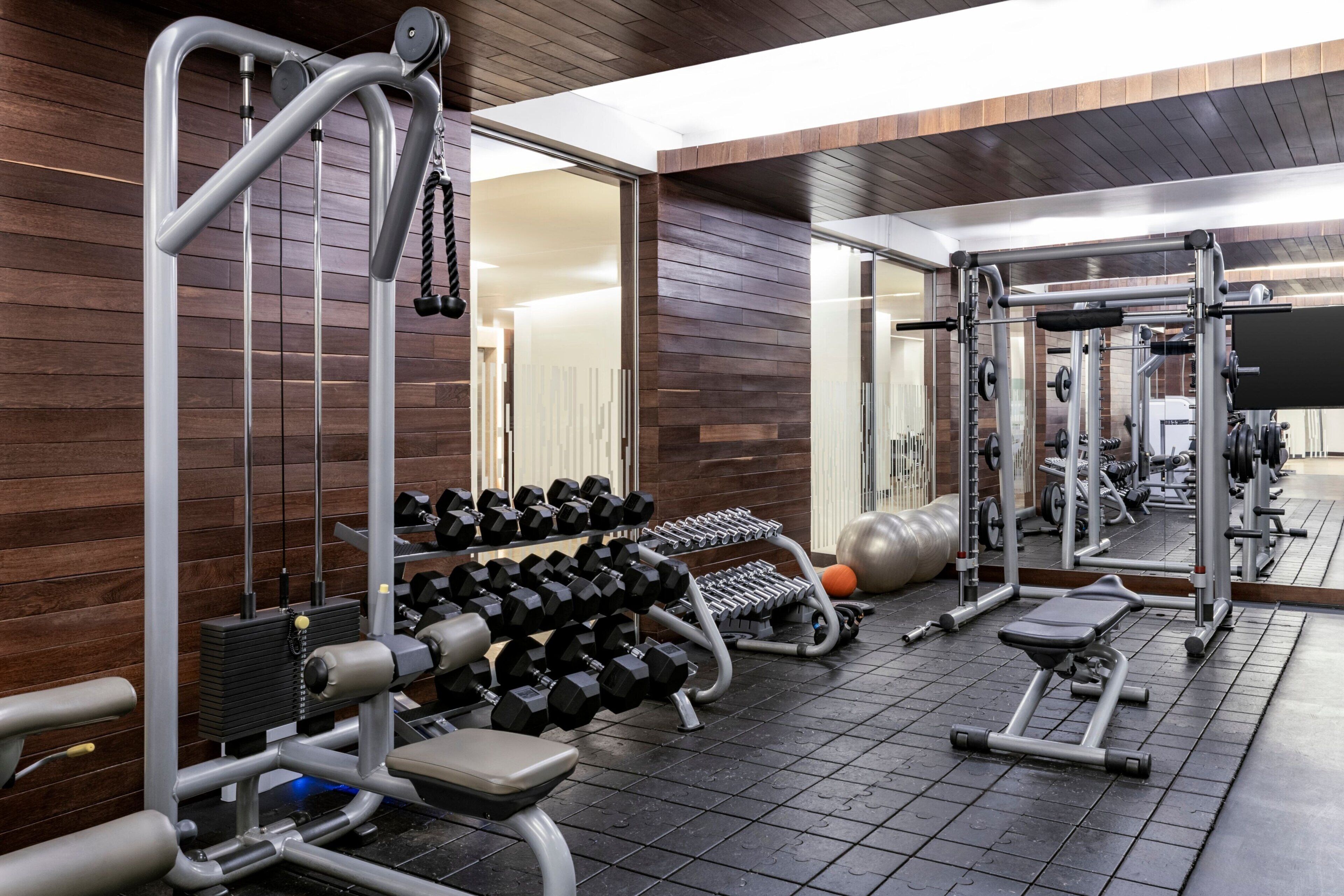 A gym with weightlifting equipment, dumbbells, and exercise machines.