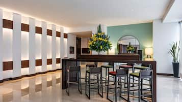 Un hall d’entrée moderne avec un comptoir d’accueil, des tabourets de bar et un grand miroir.
