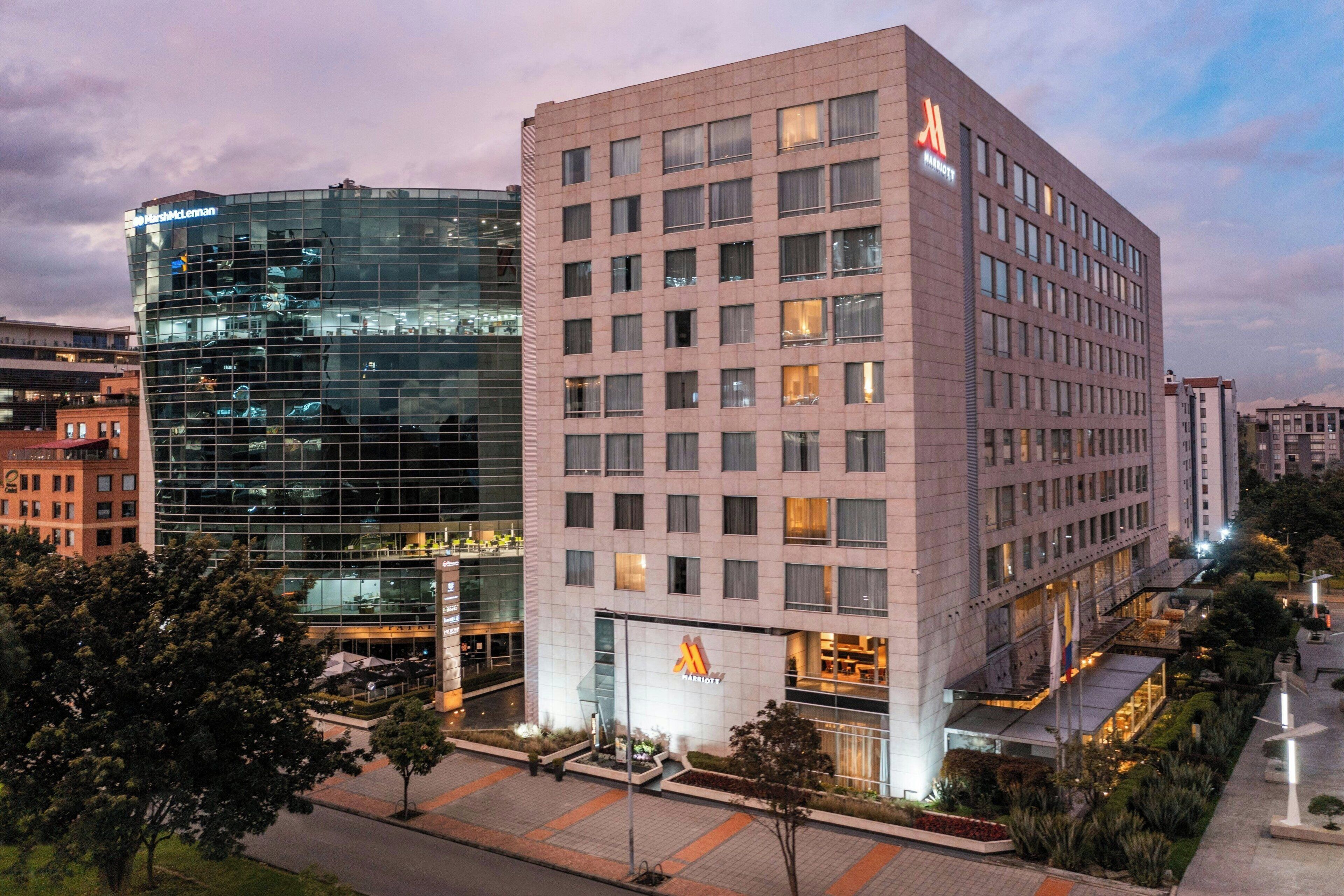 A modern hotel with a glass facade and a classic building next to it.