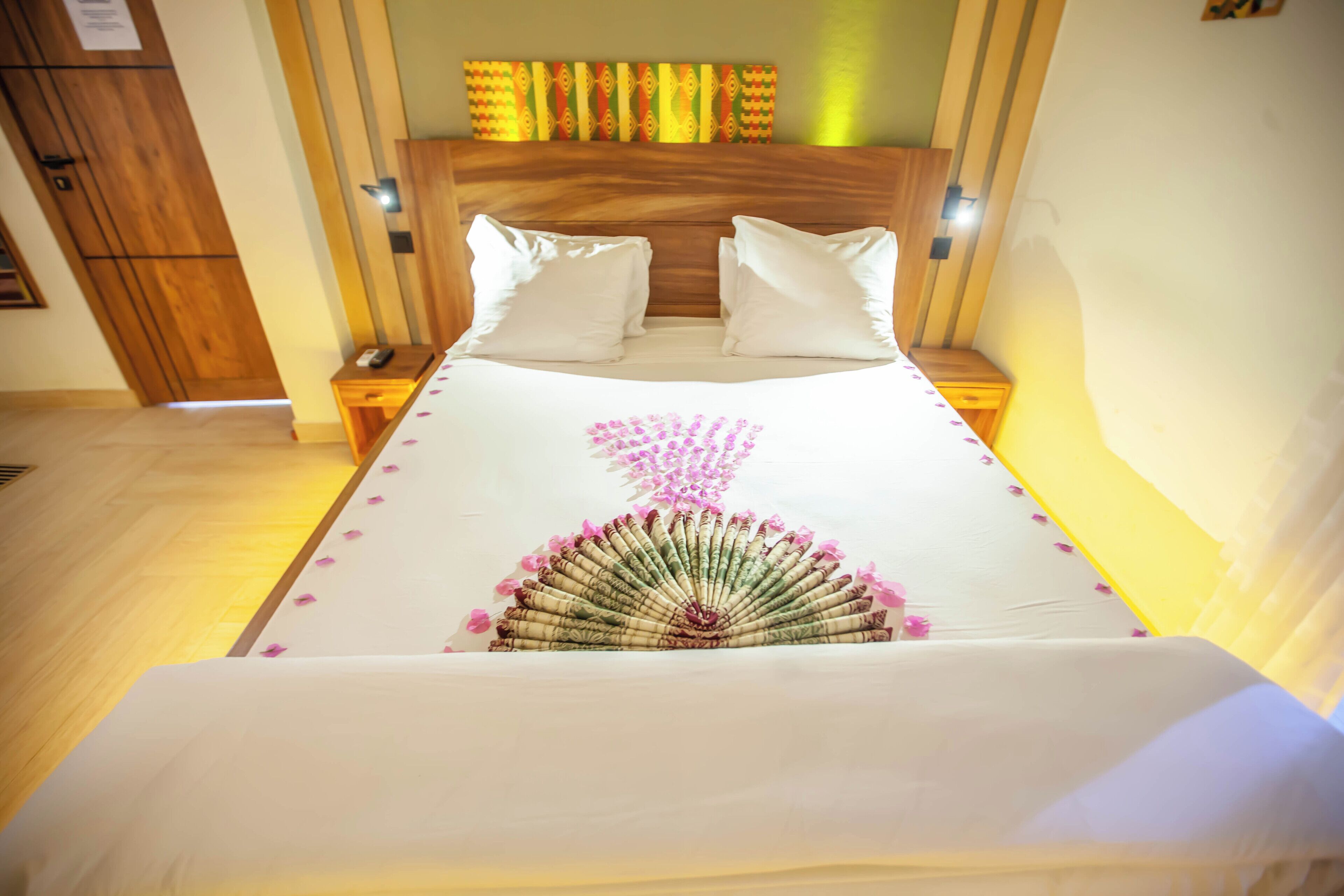 A neatly made bed with white linens and a decorative pink floral arrangement on the bedspread.
