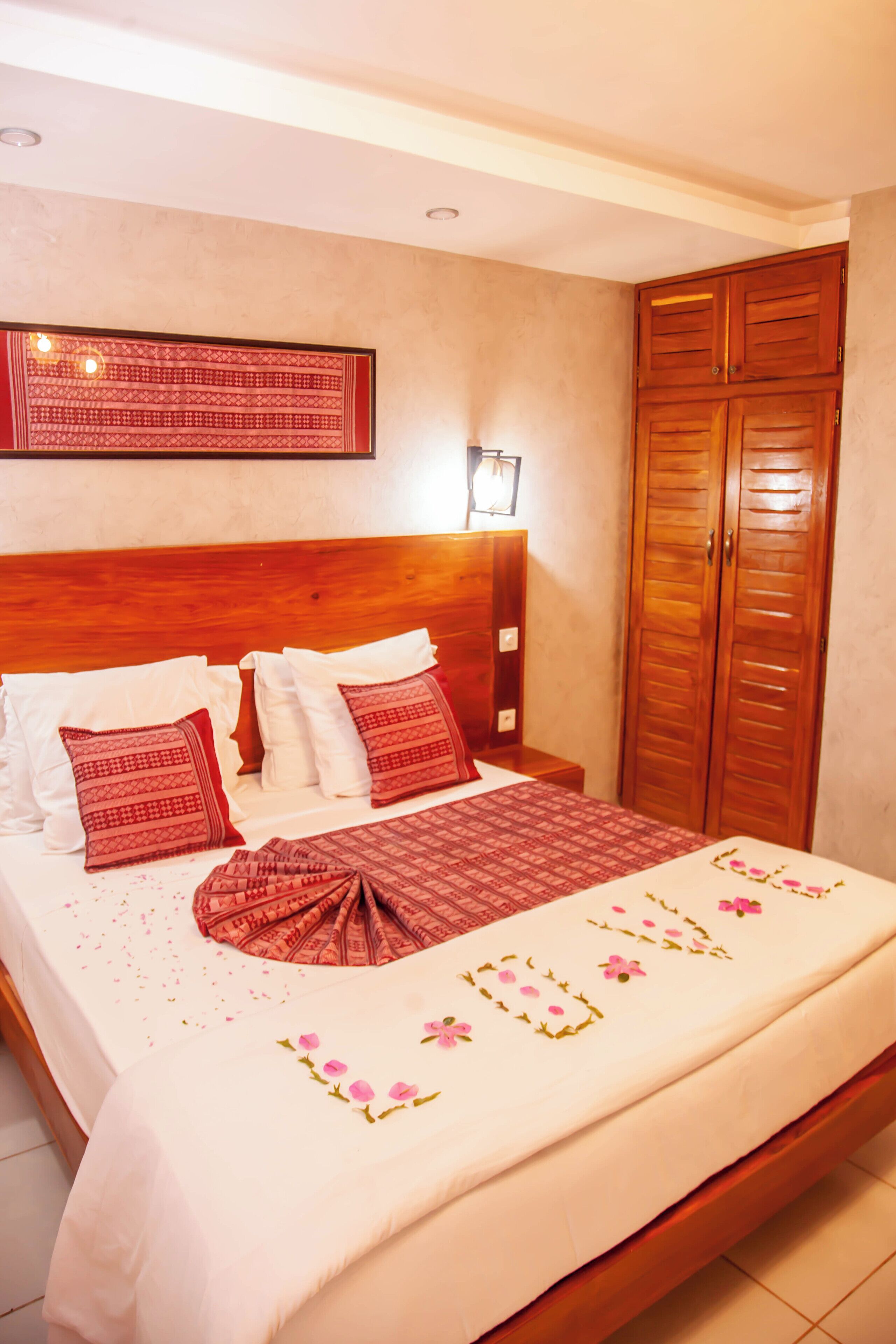 A neatly made bed with a floral bedspread, a wooden headboard, and a wardrobe with double doors.