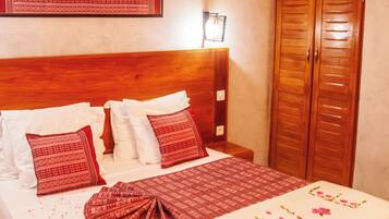 A neatly made bed with a floral bedspread, a wooden headboard, and a wardrobe with double doors.