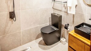 A modern bathroom with a toilet, bidet, and a sink with a mirror. - Hotel Flamboyants (Mbour)