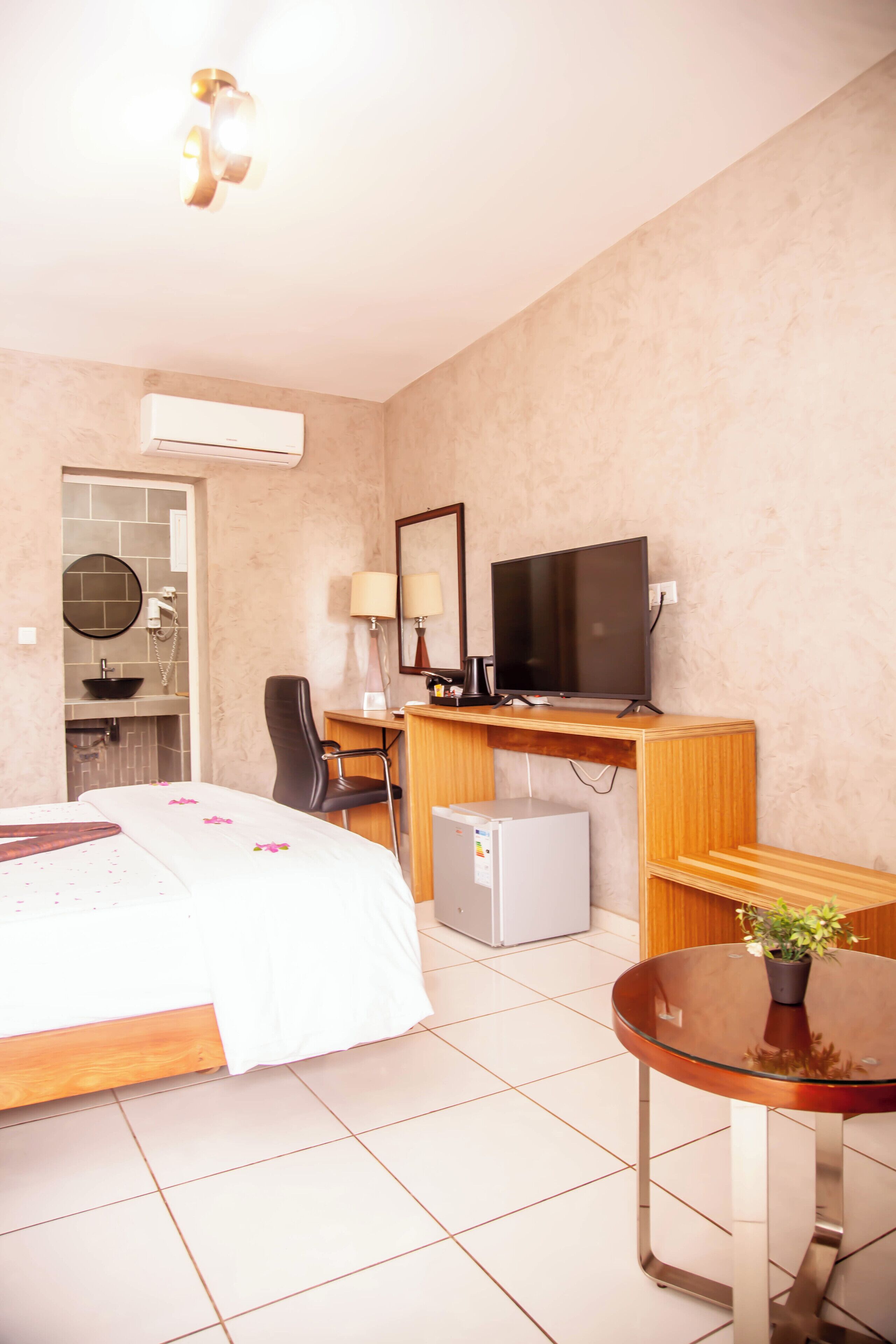 A hotel room with a bed, desk, chair, television, and a small refrigerator.