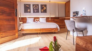 A modern bedroom with a wooden bed, a bedside table, a chair, and a fruit bowl on the floor. - Hotel Flamboyants (Mbour)