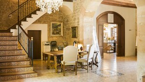 Un intérieur spacieux comprenant un escalier, un lustre, un coin repas et une vue sur une autre pièce.